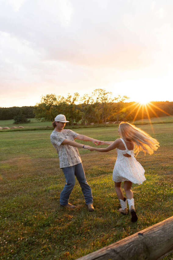 Couple dancing together at golden hour in a field
