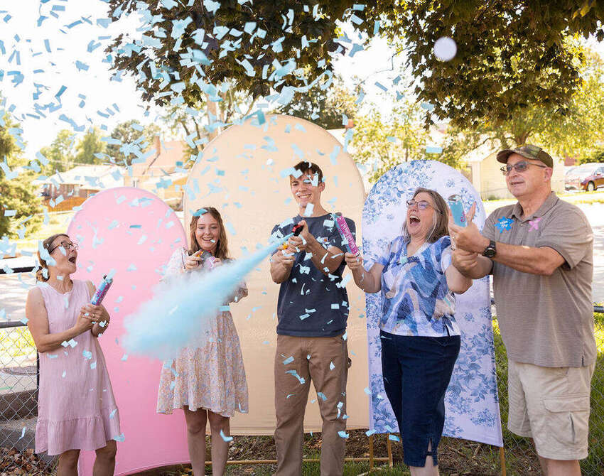 Family celebrating a gender reveal with blue confetti poppers