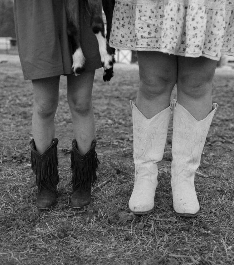 Black and white detail of cowgirl boots on a farm