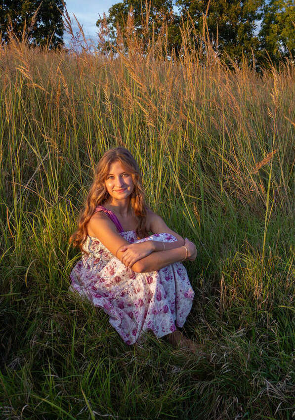 Senior portrait of a girl sitting in tall grass