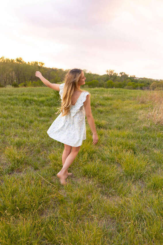 Senior girl twirling in a field at sunset