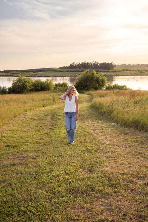 Senior girl walking a grassy path by a lake