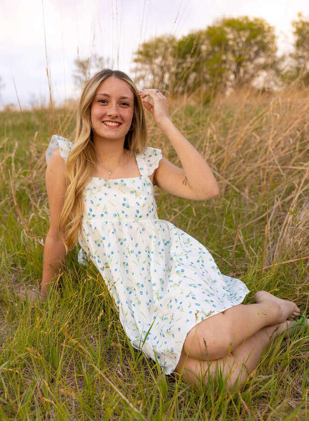 Senior girl sitting in the grass in a floral dress