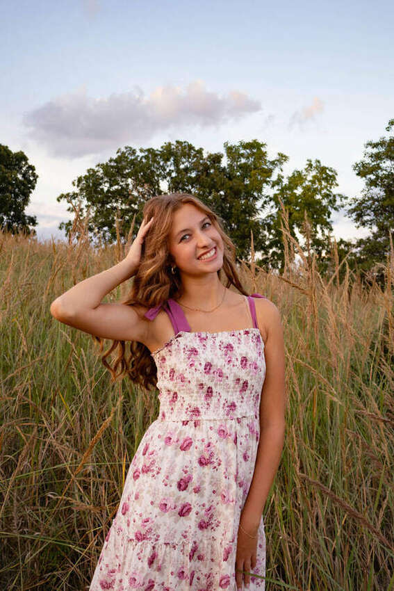 Senior portrait of a girl in a floral dress touching her hair