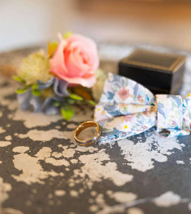 Wedding ring and bow tie on a vintage tray with a rose