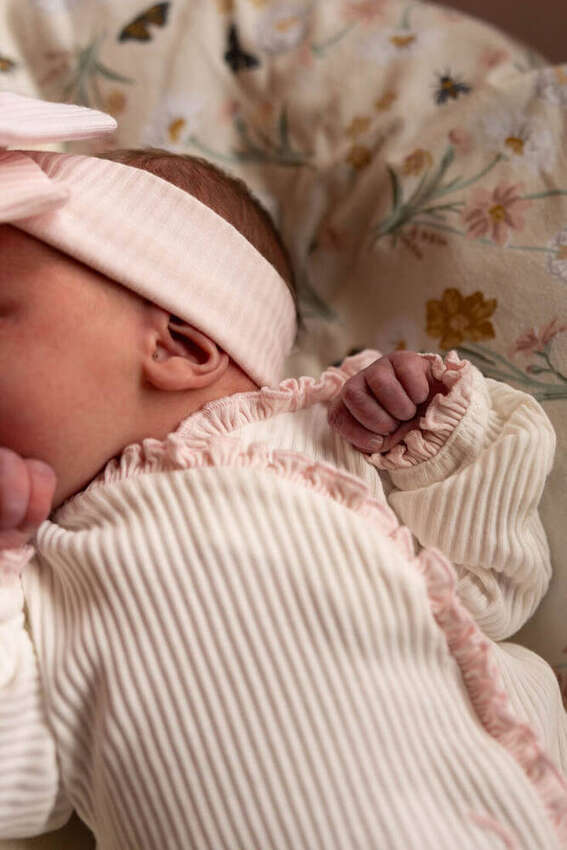 Close-up of a newborn baby's ear and hand