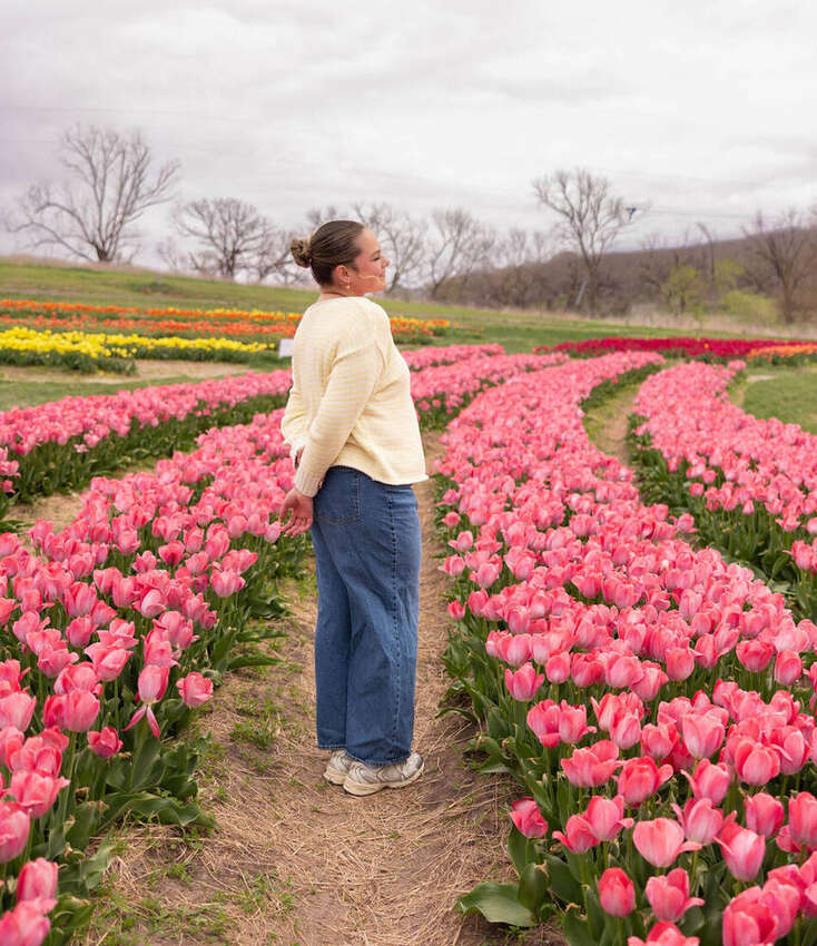 Woman standing among pink tulips, seen from behind