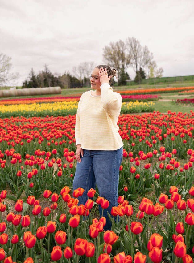 Woman standing in a field of pink tulips, smiling