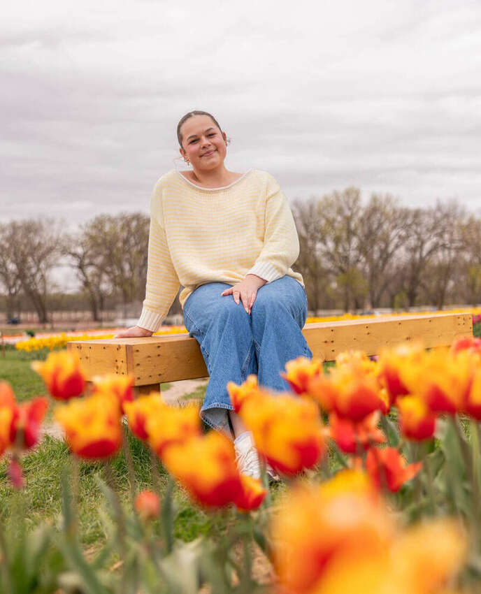Woman sitting on a bench in a field of orange tulips